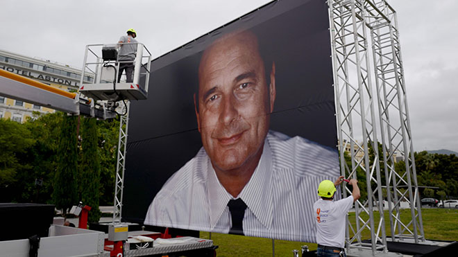 عامل يضع صورة عملاقة للرئيس الفرنسي السابق الراحل جاك شيراك في مدينة نيس الفرنسية 